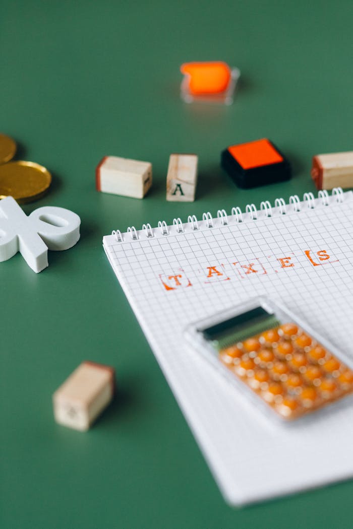 Close-up of calculator and stamped taxes on a notebook with green background.